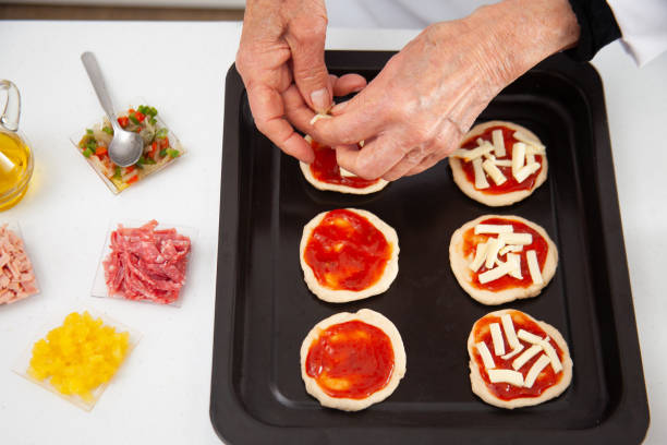 istock Adding toppings to the mini pizzas. Adding cheese. Delicious homemade mini pizzas preparation. 1616808216