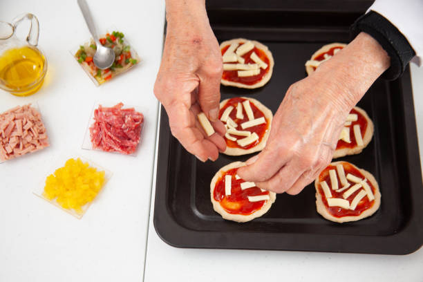 istock Adding toppings to the mini pizzas. Adding cheese. Delicious homemade mini pizzas preparation. 1616808403