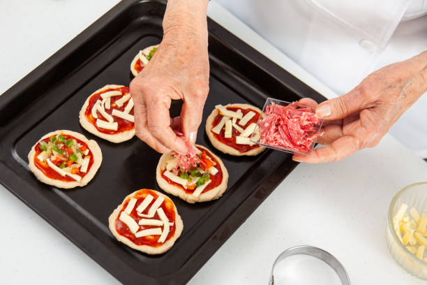 istock Adding toppings to the mini pizzas. adding salami. Delicious homemade mini pizzas preparation. 1616808700