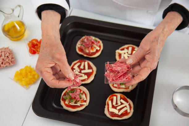 istock Adding toppings to the mini pizzas. adding salami. Delicious homemade mini pizzas preparation. 1616809231