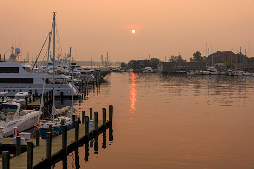 Canadian wildfires smog aftermath. Yachts and ships docked in the harbor on the water bay. Sunset covers jetty on Marina port on Severn River, Annapolis, MD