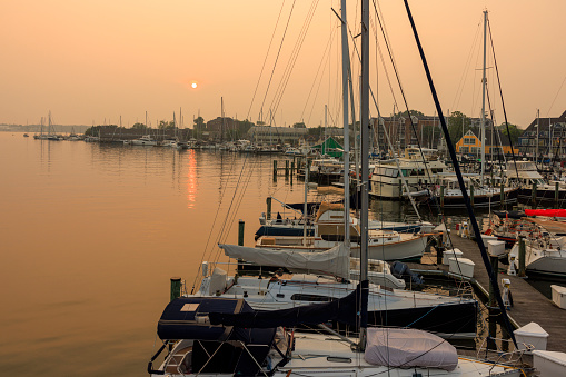 Canadian wildfires smog aftermath. Coastal features at sunset: Boats and yachts moored in the harbor on the water bay of Severn River, Annapolis, Maryland