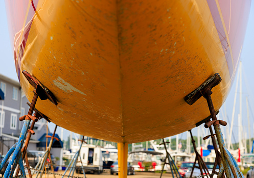 Visible signs of red rust and corrosion on the underside of a nautical vessel in the port. Close up, selective focus on parts of the boat bottom. Annapolis, Maryland