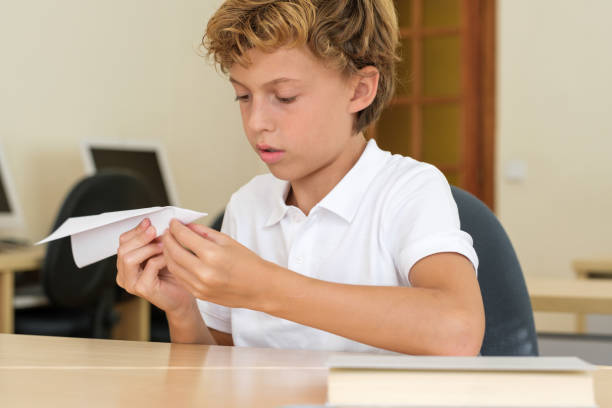 istock Serious boy making paper airplane at school 1616814239
