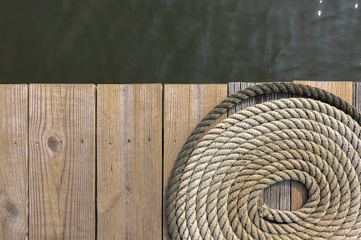 Coiled boat rope on wooden planks of jetty in Annapolis, MD. Top view, copy space