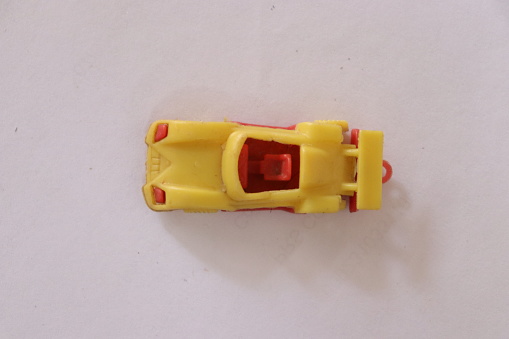 Top angle shot of a small Racing sports car toy in red and yellow colour on a white isolated background