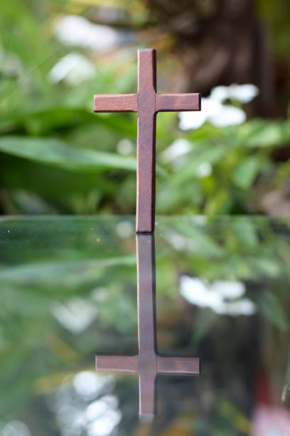 istock cross representing God in Christianity is placed on mirror and its reflection can be seen on blurred background of nature. cross on background is blurred and there is Copy Space on side for text. 1616825300