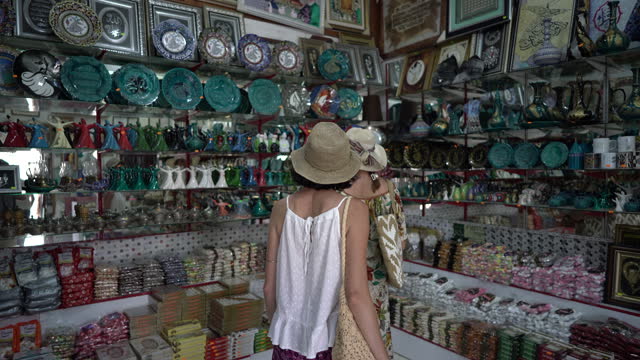 Two female friends shopping at the souvenir bazaar market shop.