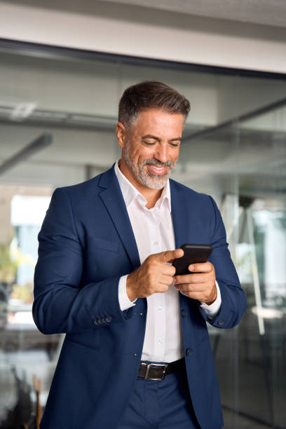 istock Digital technology application and solutions for business success development. Vertical photo of mature Latin businessman holding smartphone in office. Middle aged manager using cell phone mobile app. 1616831308