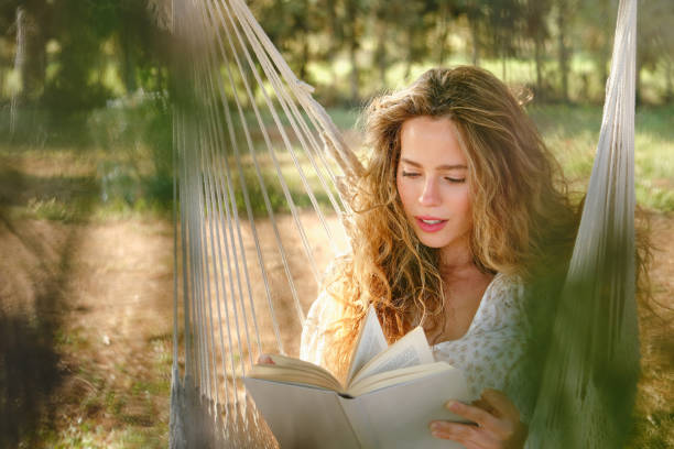 istock Young female reading book in garden 1616838287