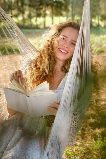 istock Delighted female enjoying reading on hammock 1616839937