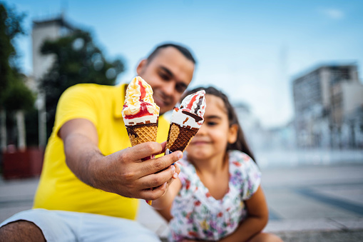 Young father with daughter eating ice cream in the city