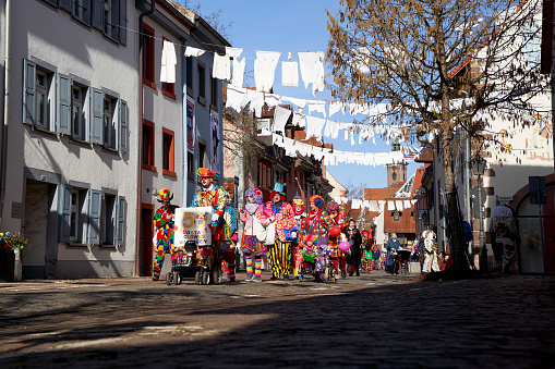 Villingen, Germany - February 20, 2023: Carnival parade with group of clowns. Decorated street with linen.