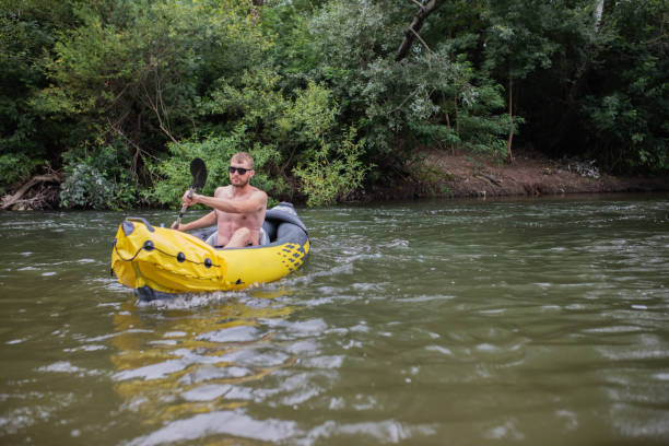 istock Young adventurous bearded man is rowing with an oar on the river in his yellow inflatable canoe. 1616883761
