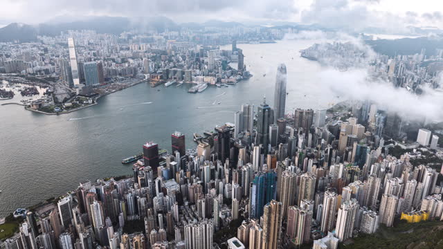 Above cloud cityscape view of Hong Kong island, drone aerial hyperlapse time lapse. Skyscraper buildings in financial district, ship transportation on Victoria harbour. Asia tourism travel concept