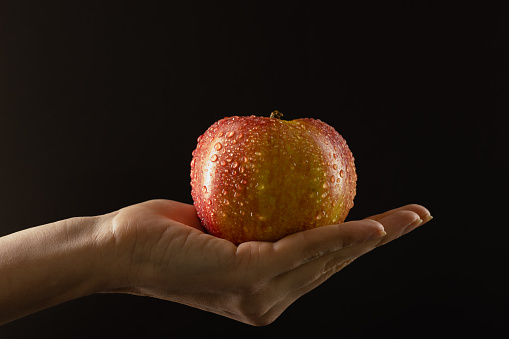 IMAGE MADE IN STUDIO OF ONE RED APPLE FRUIT ON BLACK BACKGROUND WITH COPY SPACE.