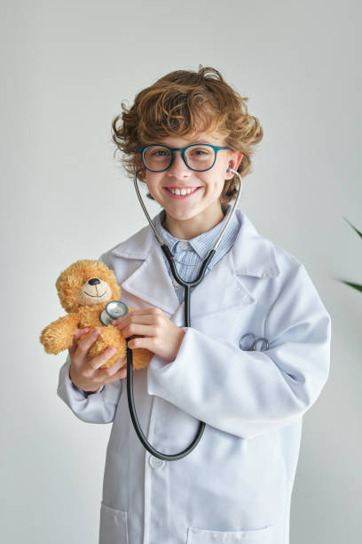 istock Cheerful boy in medical uniform examining toy bear with stethosc 1616911476