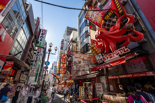 Osaka, Japan - August 19, 2022 : People walk through the Dotonbori district of Osaka, Japan. Dotonbori district is a famous tourist destination in Osaka, Japan. Many restaurants are located in Dotonbori district.