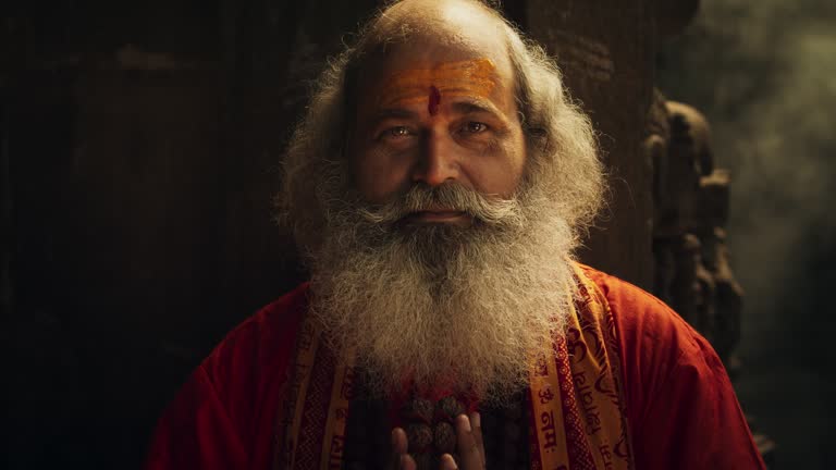 Zoom in Portrait of a Senior Hindu Monk Looking at the Camera and Smiling in an Ancient Temple. Friendly Indian Senior Man Posing as he is seeking Guidance and Wisdom from his Religion