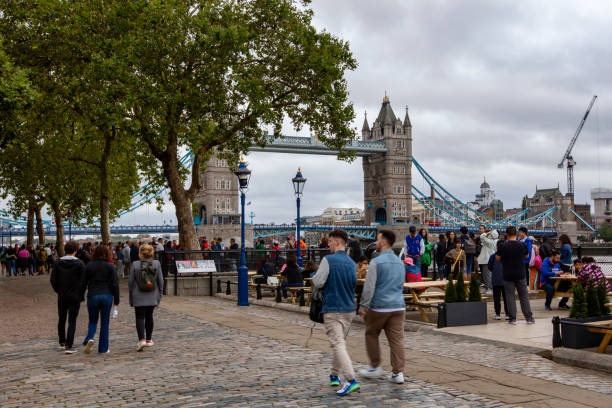 Tourists visit river Thames embankment in London with famous Tower Bridge.