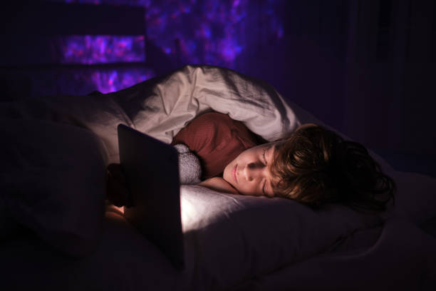 istock Boy sleeping near tablet in bed at night 1616965622