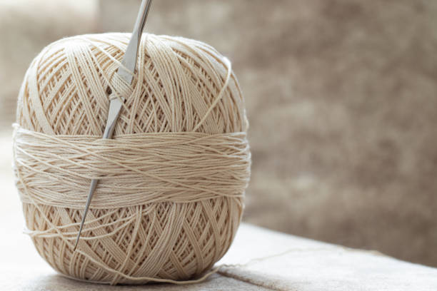 Ball of yarn with crochet hook and beige cotton thread