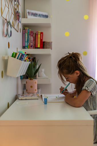 A young girl doing homework in her room.