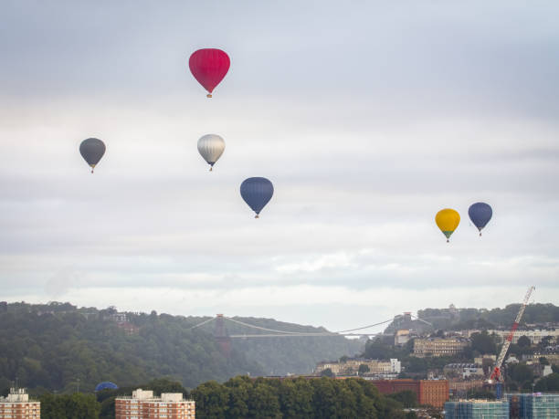 A collection of hot air balloons flying over Clifton Suspension Bridge in Bristol UK, as part of the Bristol International Balloon Fiesta 2023