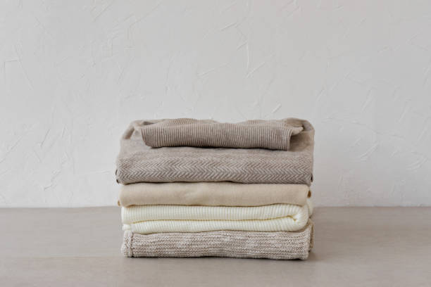 istock Minimalist neutral pastel beige wool, cashmere knitted sweaters stack on beige table on empty white wall background. Autumn, fall fashion woman clothes, knitwear wardrobe 1617056385