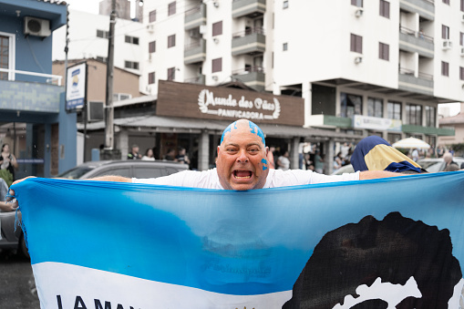 Canasvieiras Florianopolis Brazil - December 18, 2022: The man is happy celebrating with the Argentine flag the triumph of Argentina.