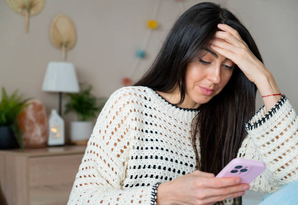 istock Sad Woman  using her phone at home 1617092898
