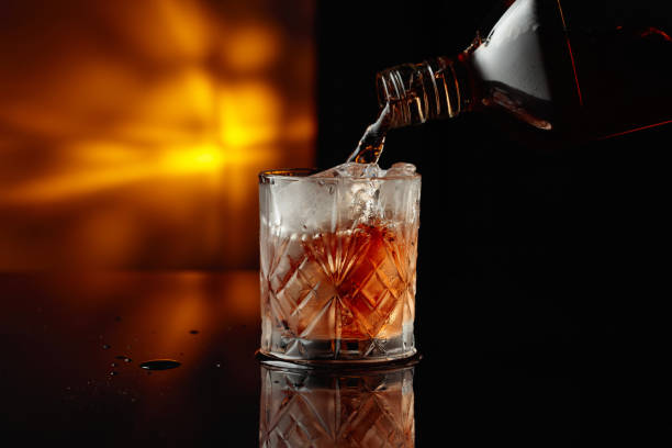 istock Pouring whiskey from a bottle into a glass with ice. 1617105198