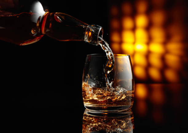 Pouring whiskey from a bottle into a glass. stock photo