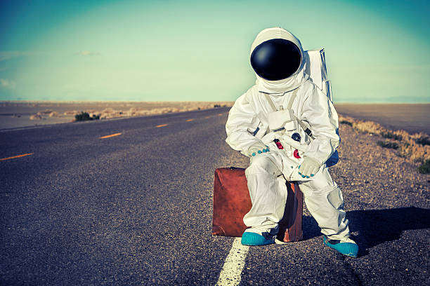 Vintage Astronaut Sitting On Luggage Waiting For A Ride Vintage Astronaut Sitting On Luggage Waiting For A Ride. This stock image has a horizontal composition. hitchhiking stock pictures, royalty-free photos & images
