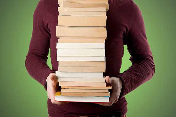 giovane uomo portare libro pila su sfondo verde - student effort book carrying foto e immagini stock