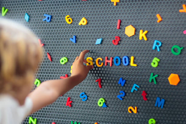 istock Boy spelling out the word school. Magnet letters. 1617155396