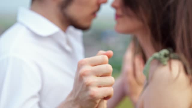 Man and woman kiss with baptized hands on blurred background