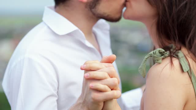 Man and woman kiss with baptized hands on blurred background