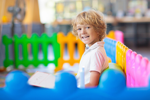 Little boy in kindergarten or daycare. Child playing with colorful educational toys in preschool. Kids play in indoor playground. Early education and child care. Student in primary school class.