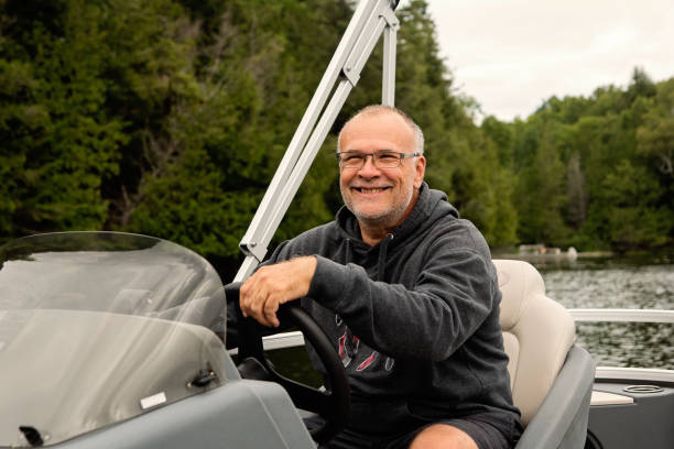 istock Senior man driving his pontoon boat on a lake. 1617161897