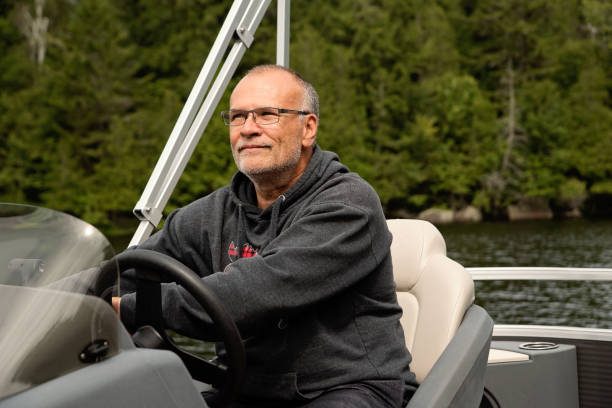 istock Senior man driving his pontoon boat on a lake. 1617162175