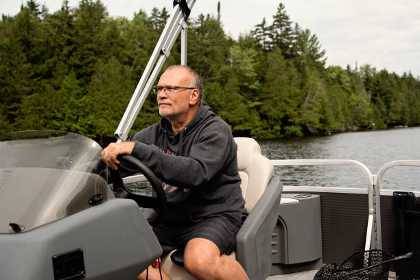 istock Senior man driving his pontoon boat on a lake. 1617162438