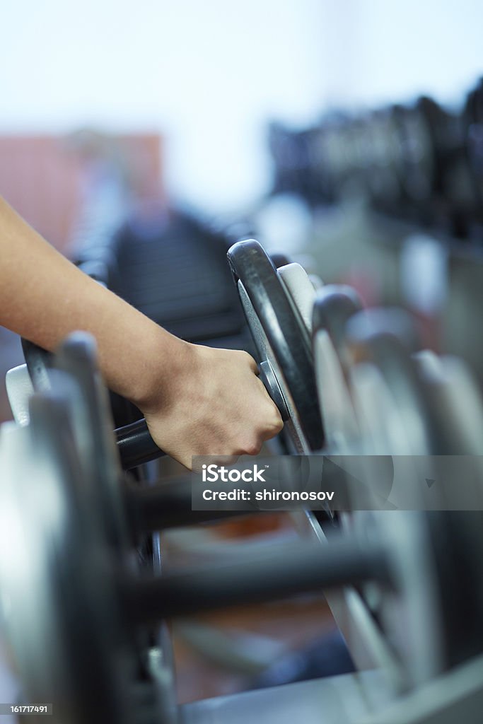 Taking barbell Image of female hand taking barbell from row of barbells in gym Activity Stock Photo