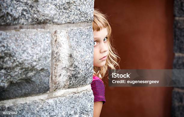 Poco Chica Rubia Vista Desde Detrás De La Pared Foto de stock y más banco de imágenes de Aire libre - Aire libre, Belleza, Cara humana