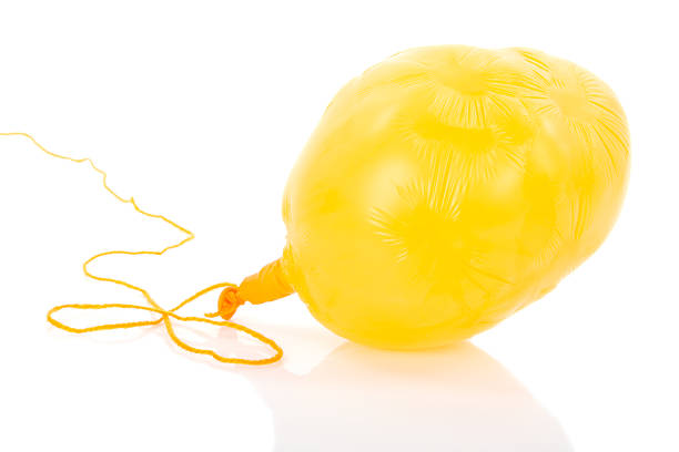 Deflated yellow balloon at a rope; isolated over white