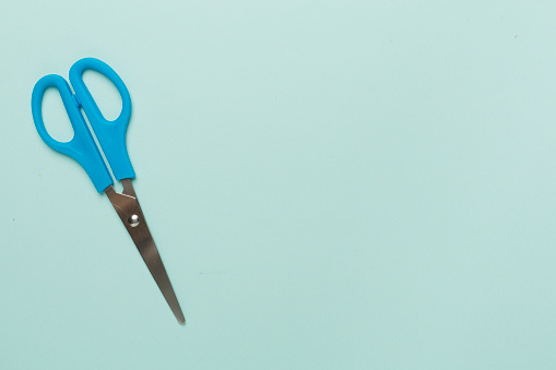 Blue scissors on color backgroung, top view