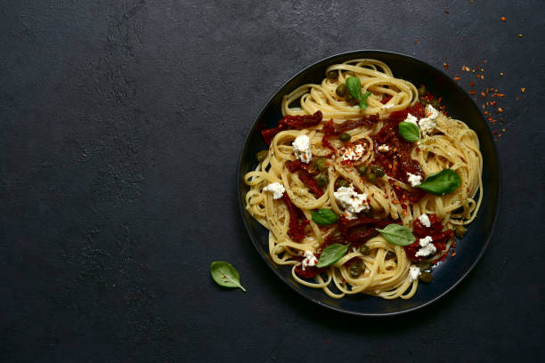 istock Pasta bavette with dried tomatoes, kapers and ricotta. Top view with copy space. 1617230487