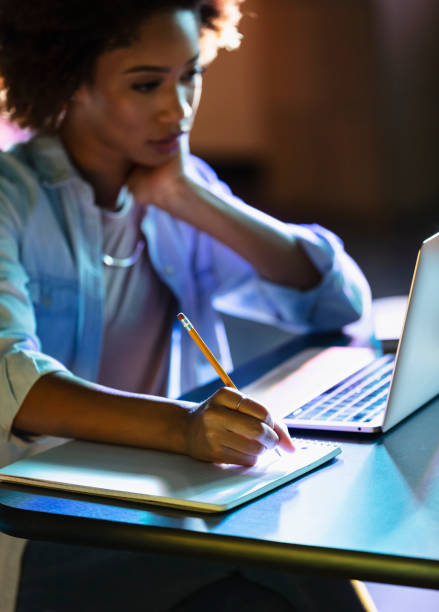 istock Young African-American woman using laptop, writing notes 1617243927