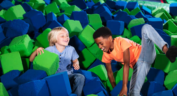 Two multiracial boys playing in a pool of foam blocks