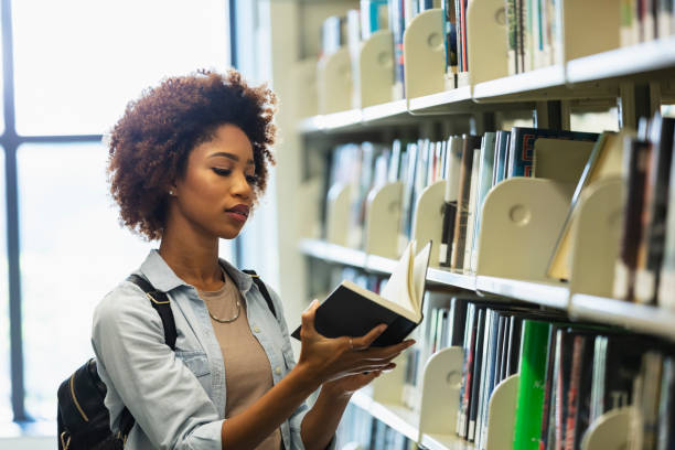 istock Young African-American woman in library looking for book 1617243979